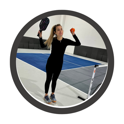 Pickleball Bits Chief tester of women's pickleball kit wearing black leggings a black shirt and holding the MTEN pickleball set paddle and ball.