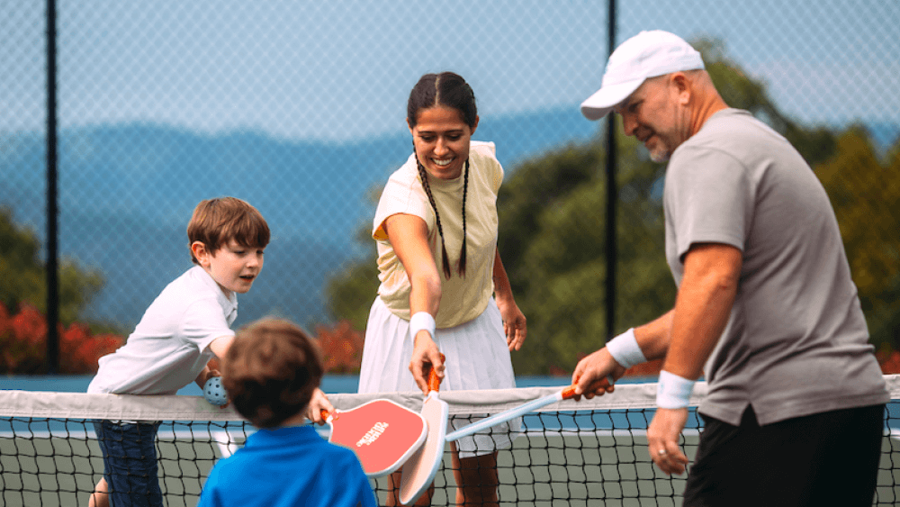 A family having fun playing pickleball, the main reason why is pickleball so popular.