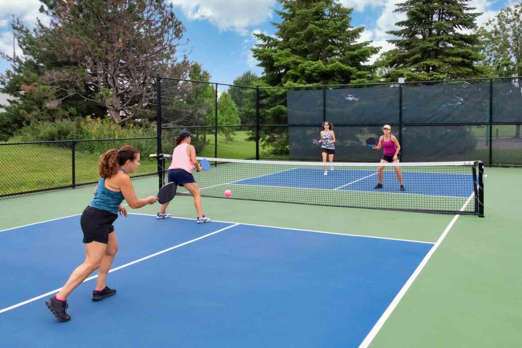 Blue Pickleball court with 4 women pickleball players in a doubles game