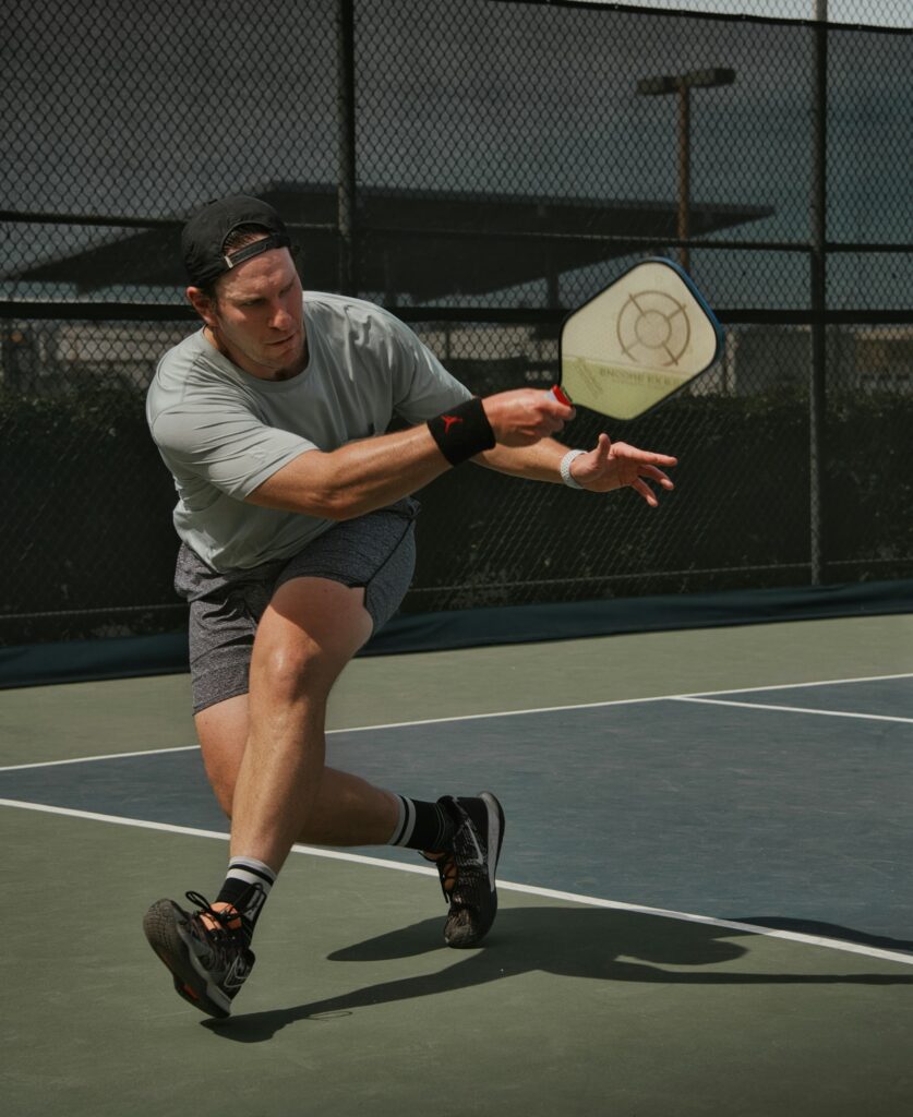 Man hitting a drive on the court and learning how does scoring work in pickleball