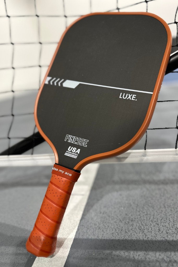 Luxe pickleball paddle reviews: Finesse paddle with black carbon fiber face and brown grip.