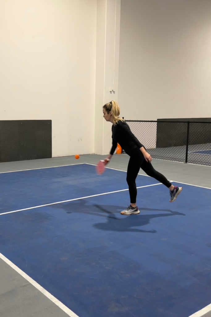 Luxe pickleball paddle reviews: blonde lady hitting an orange pickleball with the pink heart paddle.