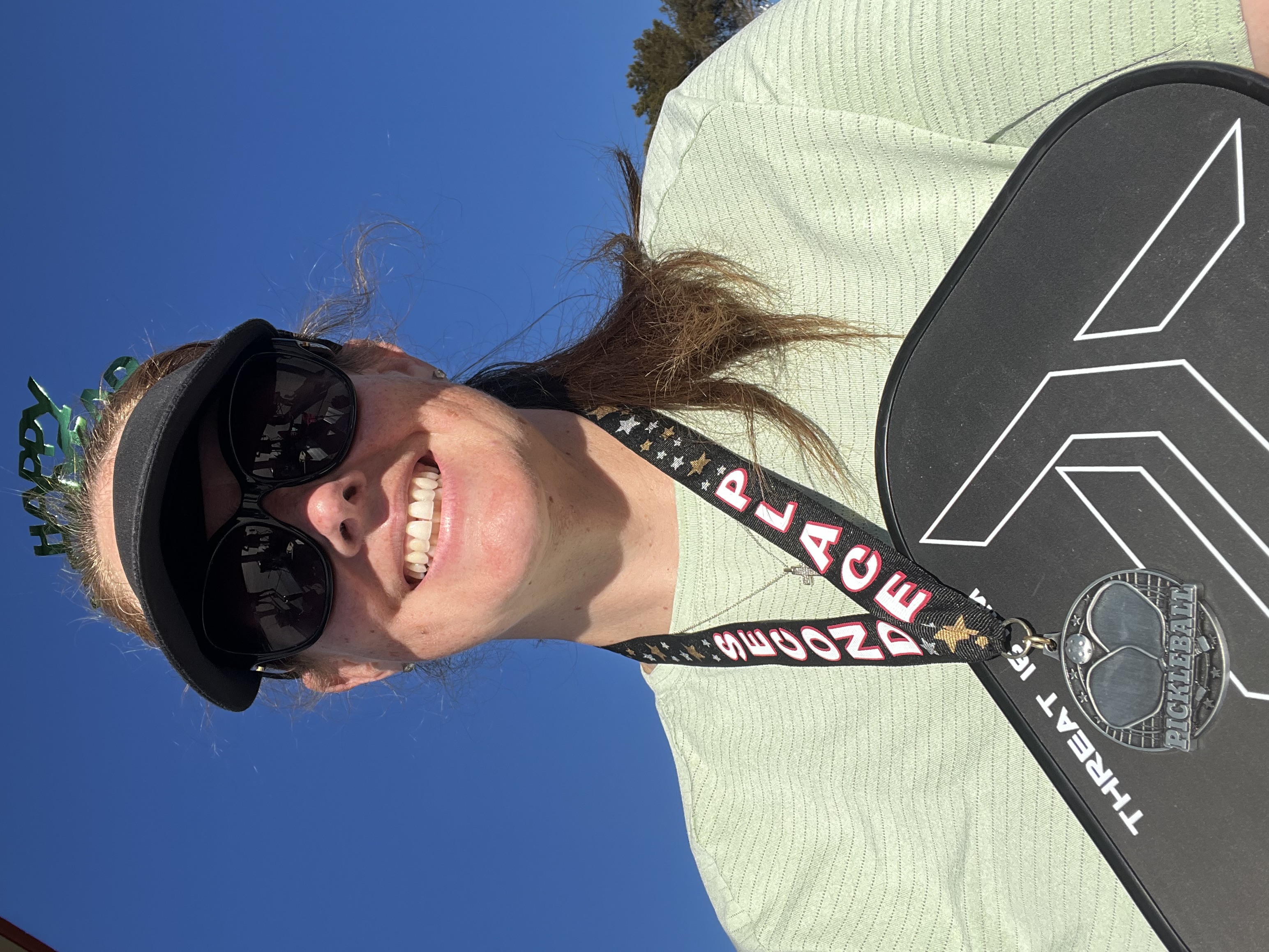 Lady with a pickleball paddle and silver medal after losing weight, showing the pickleball health benefits.