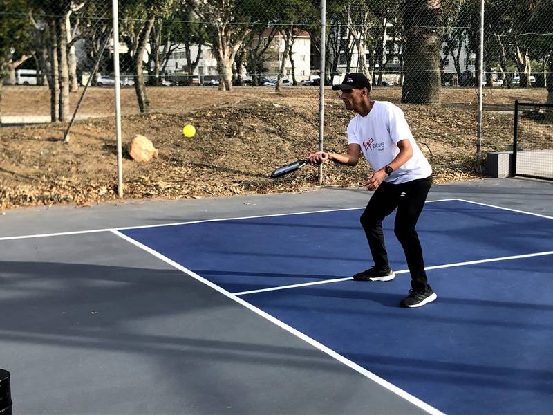 PJ from Point Pickleball Club playing a volley on a blue court.