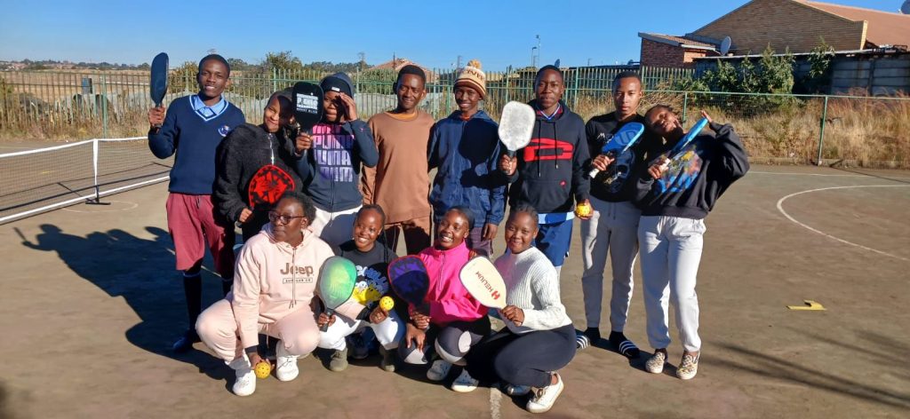 Sherry posing with the Phomolong secondary school pickleball team in Tembisa South Africa.