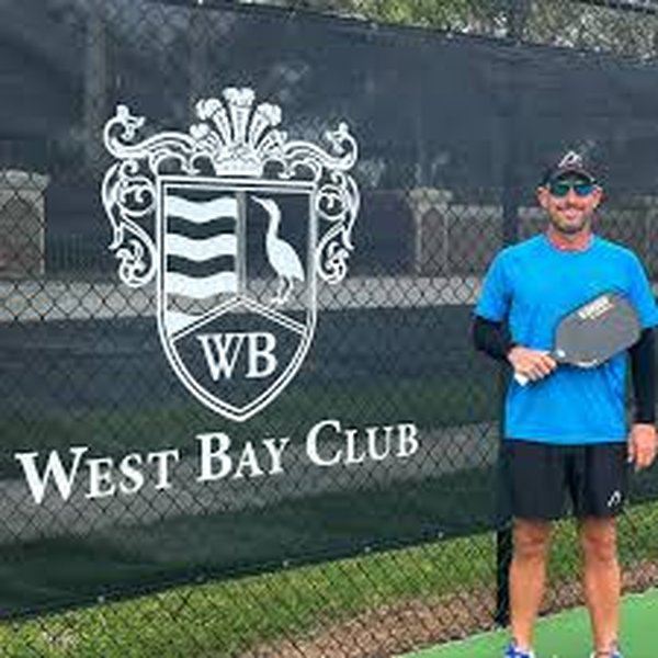 Brian Franelli, West Bay Club pickleball coach and Kondor player posing next to the WB logo.