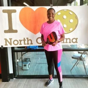 Sherry is developing pickleball in South Africa. Seen standing here in a pink shirt and black leggings.